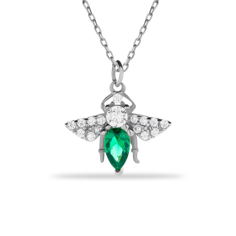 Puede incluir: Un collar de plata con un colgante de abeja con una piedra de esmeralda verde y piedras de circonita c&uacute;bica transparentes.