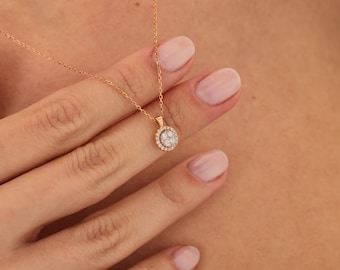 May include: A delicate gold necklace with a round pendant featuring a cluster of small diamonds set in a halo.