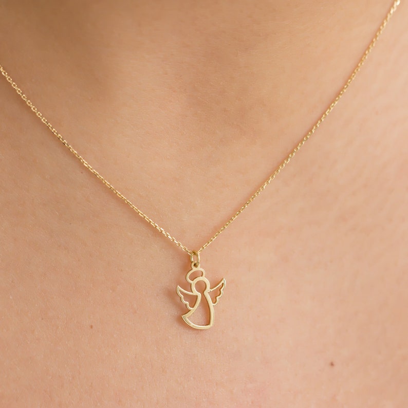 May include: A gold chain necklace with a delicate angel pendant. The angel is outlined in gold and has a halo.