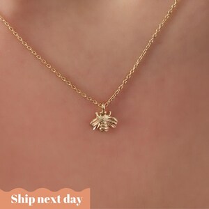 May include: A gold chain necklace with a small bee pendant.