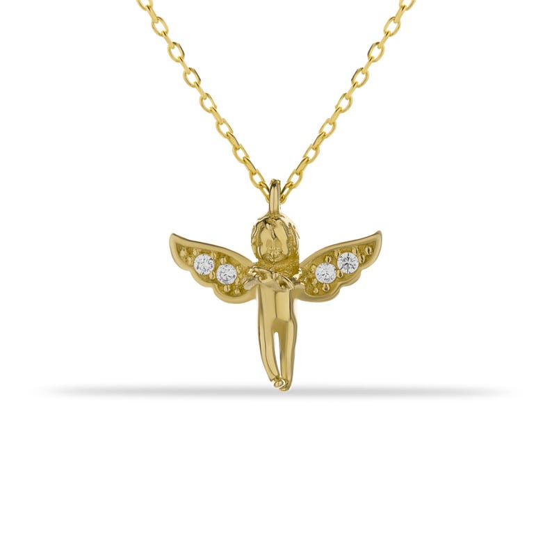 May include: A gold necklace with a small cherub pendant adorned with clear cubic zirconia stones.