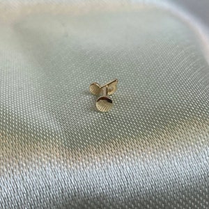May include: A gold-colored stud earring with a round top and a post.