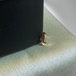 May include: A gold musical note charm attached to a black box.