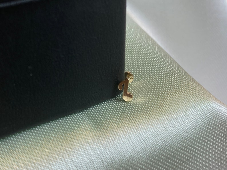 May include: A gold musical note charm attached to a black box.