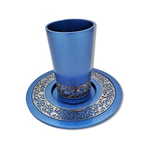 Pode incluir: Um conjunto de taça e prato Kiddush azul com um design de filigrana prateada. A taça e o prato são feitos de metal e têm um acabamento brilhante.