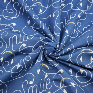 Könnte beinhalten: Blauer Stoff mit einem weißen, sich wiederholenden Muster des Wortes "lächeln" und Kopfhörerkabeln.