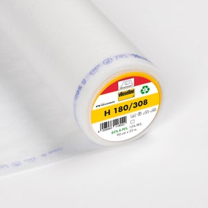 Könnte beinhalten: Eine Rolle weißer Vlieseline H 180/308  bügelbarer Einlage. Das Etikett ist gelb mit schwarzem Text und enthält Pflegehinweise. Die Einlage besteht aus 85 % R-PES und 15 % PES. Sie misst 90 cm x 25 m.