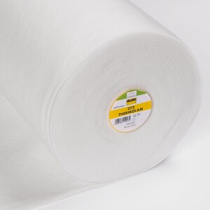 Könnte beinhalten: Eine Rolle weißen Thermolam-Stoffs mit einem Etikett mit der Aufschrift "272 THERMOLAM". Die Rolle ist 90 cm x 25 m groß. Der Stoff besteht aus 100 % PES.