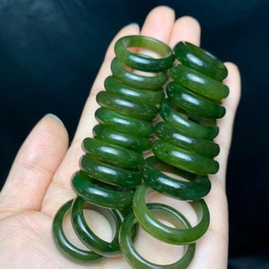 Op de afbeelding: Een stapel jadegroene ringen, elke ring is glad en gepolijst. De ringen zijn op elkaar gestapeld, waardoor een spiraalvorm ontstaat.