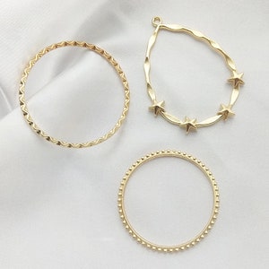 May include: Three gold-toned metal hoops, one with a wavy edge, one with a beaded edge, and one with a teardrop shape and four star accents.