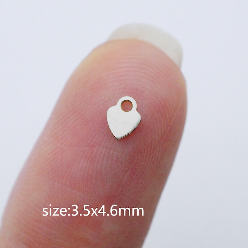 Puede incluir: Un peque&ntilde;o charm de coraz&oacute;n plateado con un bucle en la parte superior. El charm mide 3,5 x 4,6 mm.