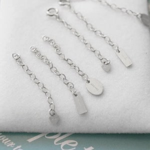 Puede incluir: Cinco extensores de cadena de plata con diferentes dijes. Los dijes incluyen un coraz&oacute;n, un rect&aacute;ngulo y un &oacute;valo con el texto "925 S925" en &eacute;l.