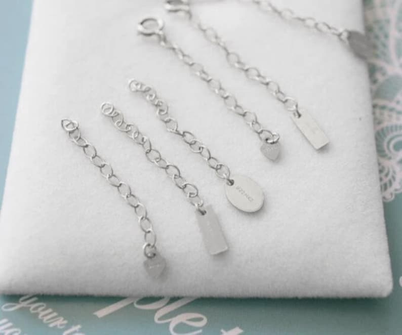 Puede incluir: Cinco extensores de cadena de plata con diferentes dijes. Los dijes incluyen un coraz&oacute;n, un rect&aacute;ngulo y un &oacute;valo con el texto "925 S925" en &eacute;l.