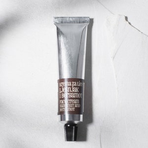 Könnte beinhalten: Eine silberne Tube Gesichtscreme mit einem braunen Etikett, auf dem "krema za lice Ljesnjak i Bergamot Face cream Hazelnut and Bergamot" steht.