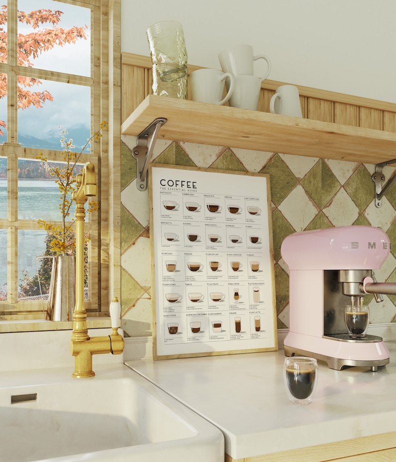 Op de afbeelding: Een roze espressomachine met een glas espresso ervoor. Een poster met de tekst "Coffee: The Essential Guide" hangt aan de muur achter de machine. De poster toont verschillende soorten koffie met illustraties van de dranken in kopjes.