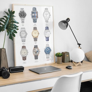 May include: A framed poster with illustrations of 12 different wristwatches. The poster is hanging on a white wall above a wooden desk with a laptop, a lamp, and a moon lamp.