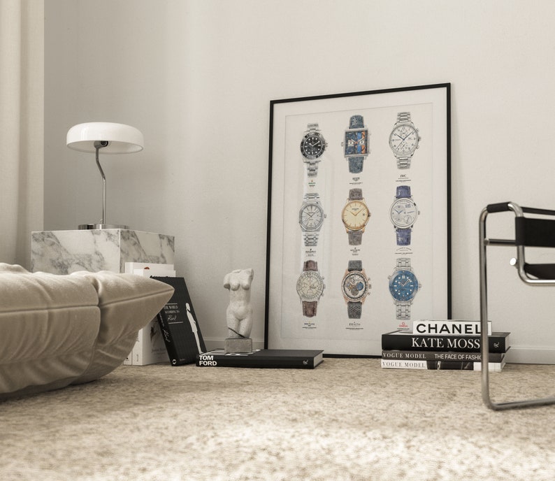 May include: A black framed poster with a white background featuring a collection of 12 different wristwatches. The watches are arranged in four rows of three. The poster is hanging on a white wall in a room with a white couch, a white lamp, and a white marble side table.