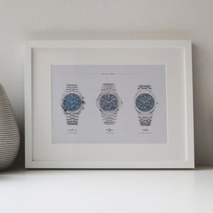 K&ouml;nnte beinhalten: Ein wei&szlig;er gerahmter Druck mit dem Titel "The Holy Trinity", der drei silberne Armbanduhren mit blauen Zifferbl&auml;ttern zeigt.
