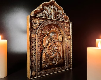 May include: A carved wooden icon depicting the Holy Family. The icon is framed in gold and features intricate details. The figures are carved in relief and painted in muted tones.