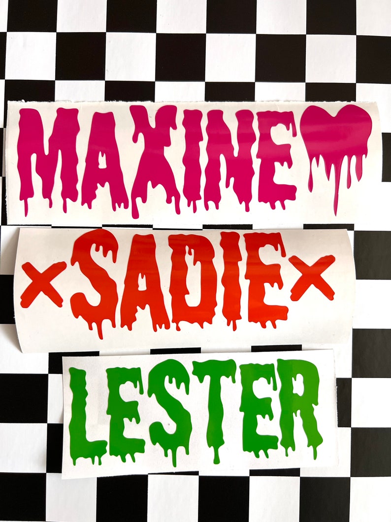 May include: Three white vinyl stickers with dripping letters spelling out the names "Maxine", "Sadie", and "Lester". The letters are pink, orange, and green, respectively.