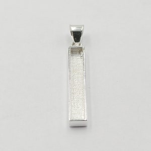 Peut inclure: Pendentif en argent de forme rectangulaire avec une finition lisse et polie. Le pendentif a une bélière en haut pour l'attacher à une chaîne.
