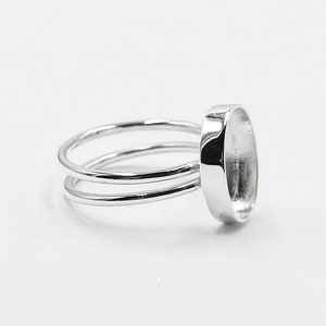 May include: Silver ring with a round bezel setting for a cabochon stone. The ring has a double band.