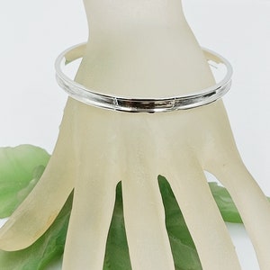 May include: A silver bangle bracelet with a textured design.