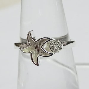 Pode incluir: Anel de prata com um design de estrela do mar e uma pequena pedra redonda cravejada com pedras menores.
