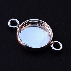 May include: Silver-toned metal pendant with a round bezel and two jump rings. The bezel is empty and ready to be filled with a cabochon.