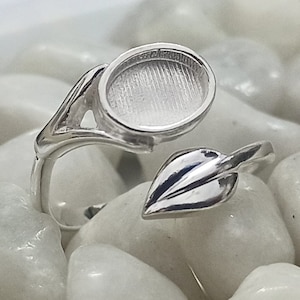 Puede incluir: Anillo de plata con un diseño de hoja y un engaste redondo. El anillo está diseñado para sujetar una pequeña piedra de cabujón.