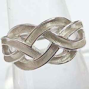 May include: A silver ring with a braided design. The ring is made of a smooth, polished metal and has a simple, elegant style.