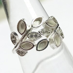 K&ouml;nnte beinhalten: Ein silberner Ring mit einem Design aus Bl&auml;ttern und kleinen, klaren Steinen.