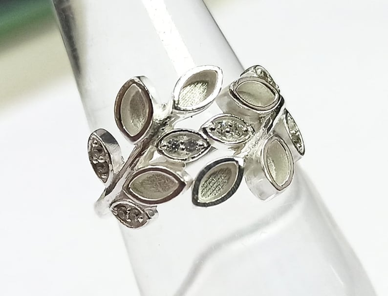 K&ouml;nnte beinhalten: Ein silberner Ring mit einem Design aus Bl&auml;ttern und kleinen, klaren Steinen.
