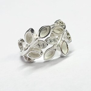 K&ouml;nnte beinhalten: Silberring mit einem Blattdesign. Die Bl&auml;tter sind in einer Reihe angeordnet und haben eine leicht erhabene Textur. Der Ring ist ein zartes und feminines Schmuckst&uuml;ck.