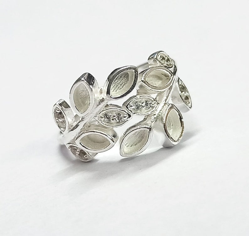 K&ouml;nnte beinhalten: Silberring mit einem Blattdesign. Die Bl&auml;tter sind in einer Reihe angeordnet und haben eine leicht erhabene Textur. Der Ring ist ein zartes und feminines Schmuckst&uuml;ck.
