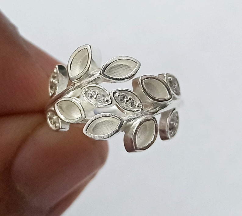 K&ouml;nnte beinhalten: Ein silberner Ring mit einem Design aus Bl&auml;ttern und kleinen klaren Steinen.