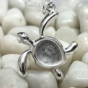 May include: Silver turtle charm pendant with a smooth, polished finish. The charm is designed to be worn on a necklace or bracelet.
