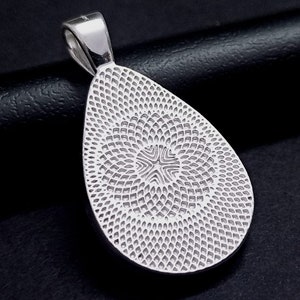 May include: Silver pendant with a teardrop shape and a textured design. The pendant has a loop at the top for attaching a chain.