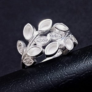 K&ouml;nnte beinhalten: Ein silberner Ring mit einem Design aus Bl&auml;ttern und kleinen, klaren Steinen.