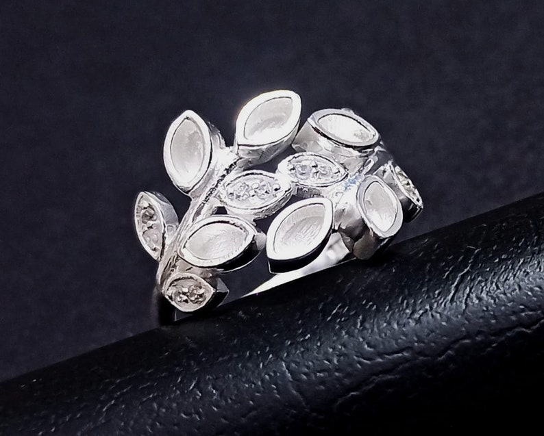 K&ouml;nnte beinhalten: Ein silberner Ring mit einem Design aus Bl&auml;ttern und kleinen, klaren Steinen.