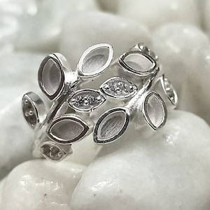 May include: Silver ring featuring a design of leaves and small clear stones.