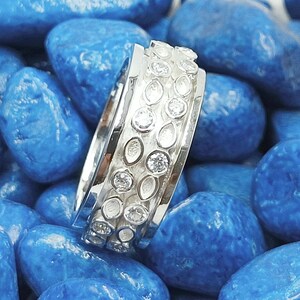 May include: A silver ring with a band of small, round, clear stones and a row of oval-shaped, white stones.