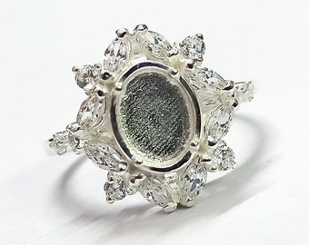 Op de afbeelding: Zilveren ring met een grote ovale zetting omringd door kleinere heldere stenen.