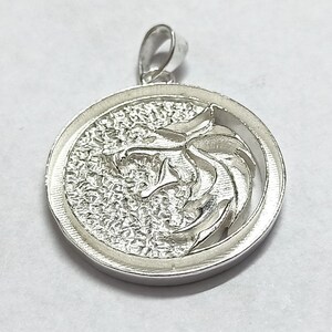 May include: Silver pendant featuring a wolf's head design in a circular frame.