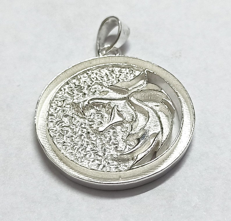 May include: Silver pendant featuring a wolf's head design in a circular frame.