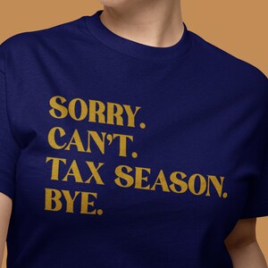 May include: A navy blue t-shirt with the text "SORRY. CAN'T. TAX SEASON. BYE." printed in gold.