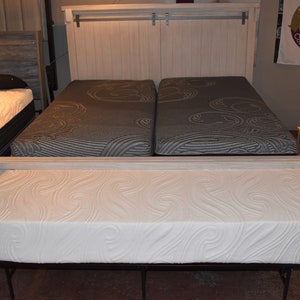 May include: Two twin-sized mattresses with a white headboard and a white footboard. The mattresses have a white and gray patterned fabric cover. A white mattress topper is on top of the mattresses.
