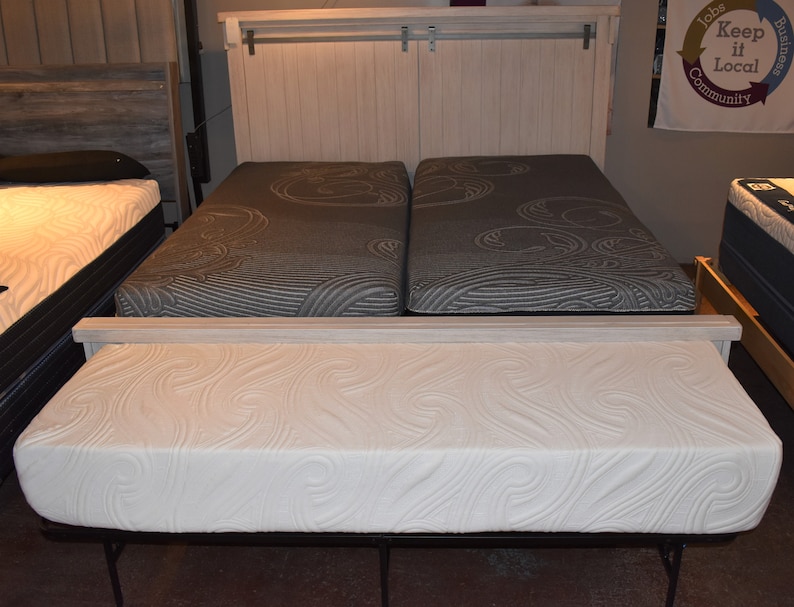 May include: Two twin-sized mattresses with a white headboard and a white footboard. The mattresses have a white and gray patterned fabric cover. A white mattress topper is on top of the mattresses.