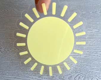 May include: A yellow sun sticker with a scalloped edge and a circle in the center. The sun has rays around it.