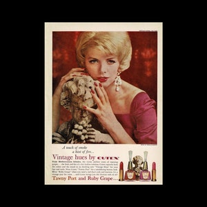 May include: A vintage advertisement for Cutex nail polish featuring a woman with blonde hair wearing a pink dress and holding a stone sculpture. The ad features the tagline "Vintage hues by Cutex" and highlights the colors Tawny Port and Ruby Grape.